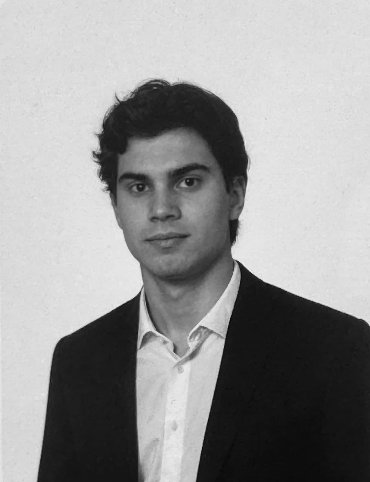 Aleksi Hartikainen in a dark jacket and open white shirt, facing the camera.